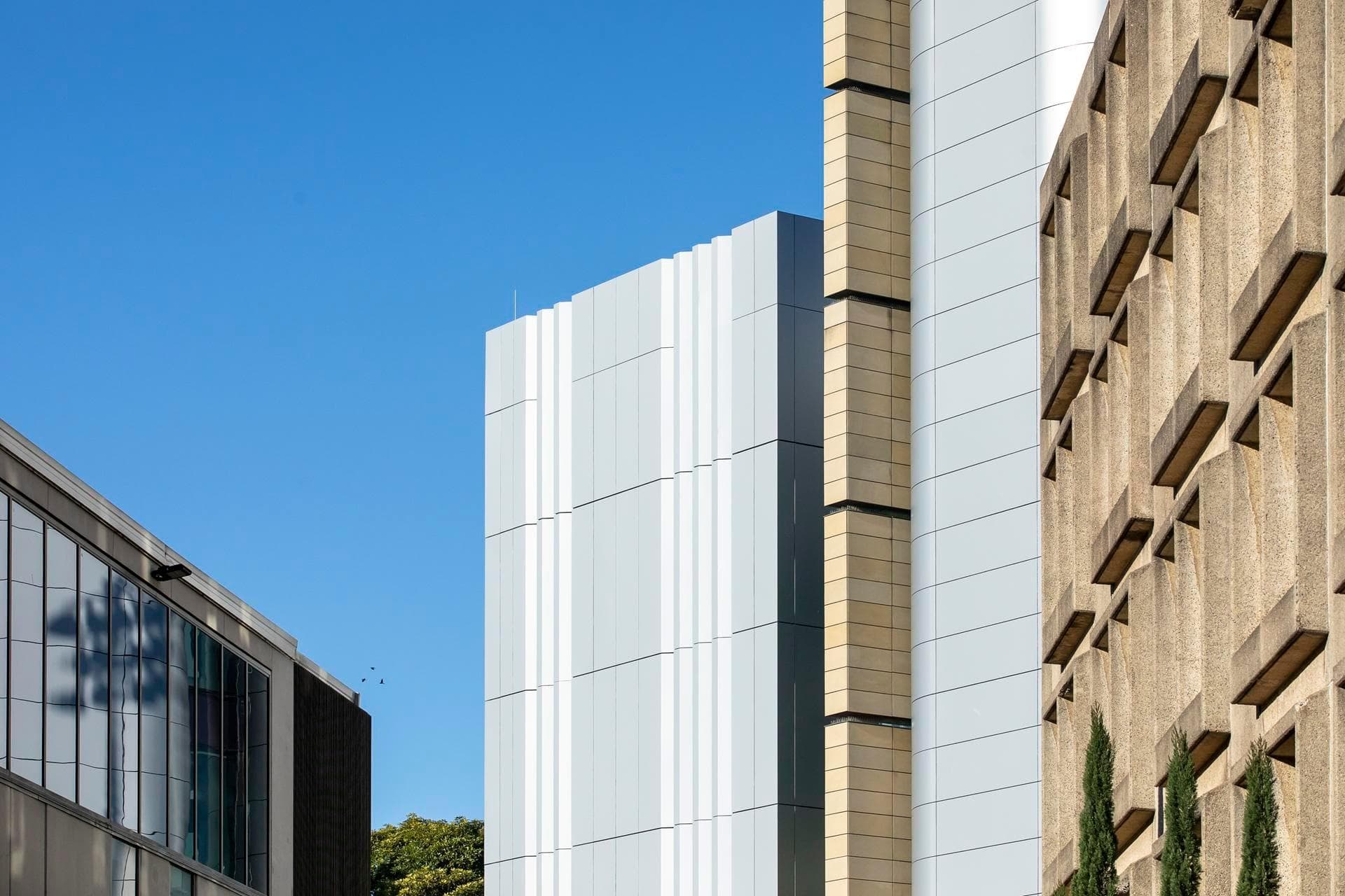 Side view of Charles Perkins Centre showing Alpolic NC silver and beige façade panels contrasted with adjacent concrete building.